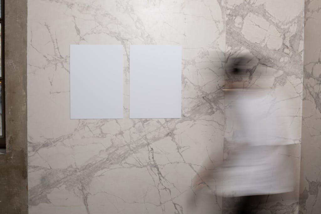 Abstract image featuring two blank papers on a marble wall and blurred motion of a person walking.